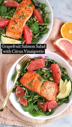 two white bowls filled with salmon and greens on top of a pink napkin next to an orange slice