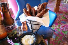 some food is sitting on a glass table with beer bottles and a basket full of churros