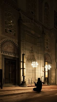 a person sitting on the floor in front of a building with chandeliers hanging from it