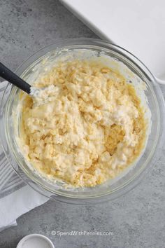 a glass bowl filled with batter on top of a gray counter next to a white dish towel