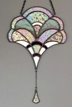 a stained glass chandelier hanging from a chain on a wall in a room