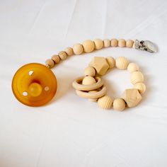 a pacifier and wooden bead necklace on a white surface with a button attached to it