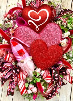 a wreath with two red hearts on top of it and ribbons around the wreaths