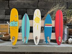 five surfboards are lined up in a row on a shelf next to a potted plant