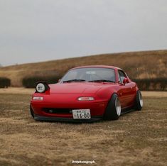 a red sports car is parked in the middle of a field with no one around it