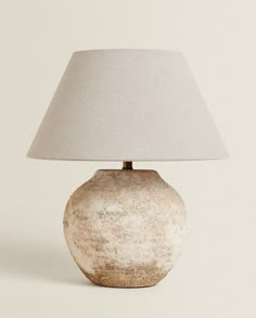 a lamp that is sitting on top of a white table with a light shade over it