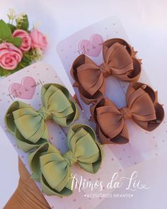 two small bows are sitting on top of each other next to a card with pink roses