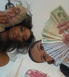 two women with money in their hands and one woman holding out her hand to the camera