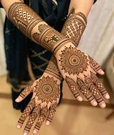 two hands with henna tattoos on them, one is showing off the intricate design