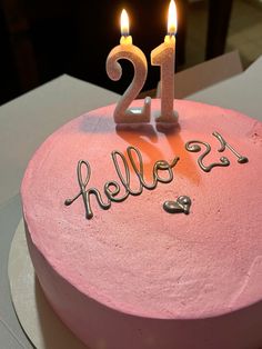 a pink birthday cake with two lit candles on it's top and the number twenty one is hello