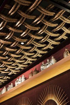 there are many vases on the shelves in this room with rope hanging from the ceiling