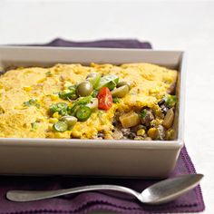 a casserole dish with vegetables in it on a purple place mat next to a fork