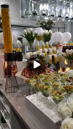 a buffet table filled with lots of food and flowers in vases on top of it