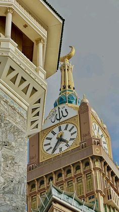 a large clock on the side of a building with a tower in the back ground