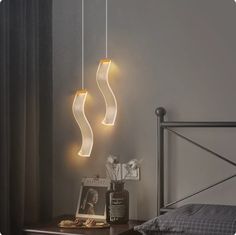 three lights hanging over a bed next to a night stand with a lamp on it