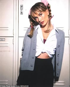 a woman in a white shirt and black skirt standing next to lockers