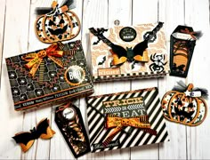 several halloween cards and tags laid out on a white wooden surface with pumpkins, bats, and spider web