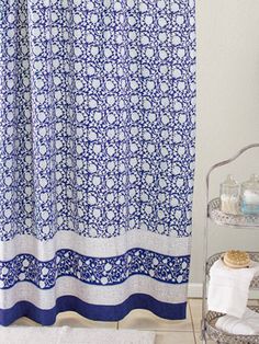 a blue and white shower curtain next to a shelf with towels on top of it