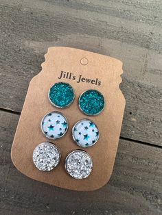 three pairs of blue and white glittered studs on top of a cardboard package