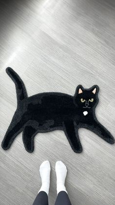 a black cat rug is on the floor next to someone's feet wearing white socks