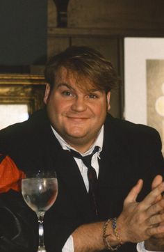 a man sitting at a table with a wine glass in front of him and smiling