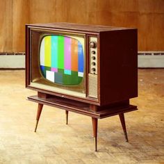 an old tv sitting on top of a wooden stand in the middle of a room