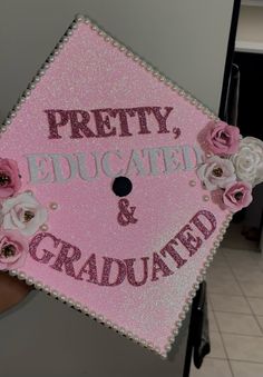 a pink graduation cap that says pretty, educated and graduated with flowers on it