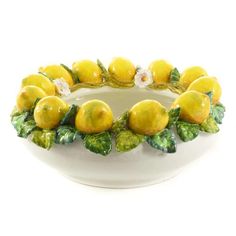 a white bowl filled with lemons and leaves