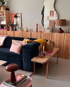 a living room filled with furniture next to a wooden table and mirror on the wall