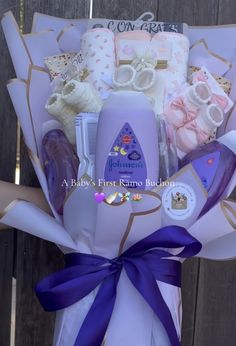 a bouquet of baby items is wrapped in purple ribbon