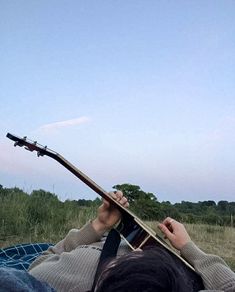 a person laying down with a guitar in their lap and looking up at the sky