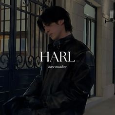 a man standing in front of a gate wearing a black leather jacket with the word harl on it