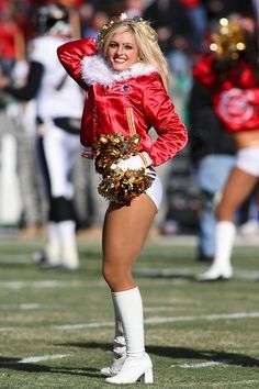 a cheerleader in red and gold uniform on the sidelines during a football game