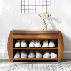 a wooden shoe rack filled with white shoes next to a vase full of dried flowers