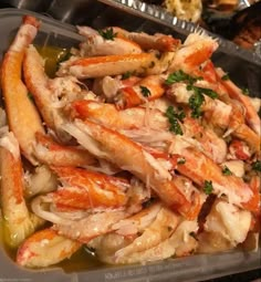 crab legs with parsley on top in a plastic container