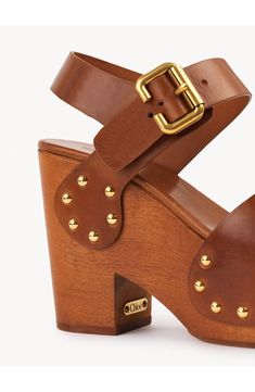 A chunky roller buckle and stud hardware add to the retro-chic allure of this leather sandal elevated on a lofty woodgrain platform and block heel. 4 1/4" heel (size 37) Adjustable strap with buckle closure Leather upper and lining/synthetic sole Made in Italy Designer Shoes This brand has B Corp certification, representing business practices with emphasis on social and environmental performance, accountability and transparency This brand meets Nordstrom Responsible Brands criteria: brand adhere Luxury Summer Clogs With Wooden Heel, Ginger Brown, Leather Clogs, Retro Chic, Sandal Women, Emphasis, Platform Sandals, Smooth Leather, Leather Sandals