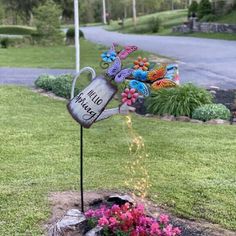 a garden stake with flowers and butterflies on it in the middle of a flower bed