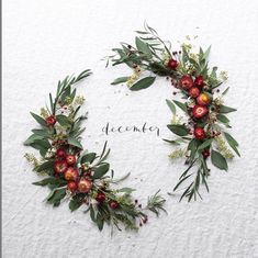 two wreaths with red berries and greenery on the side of a white wall