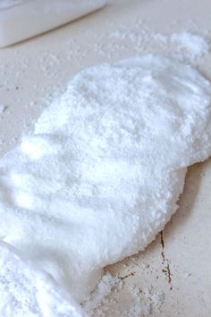 a pile of white powder sitting on top of a table next to a container of milk