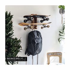 a skateboard hanging on the wall next to a backpack and tree with potted plants