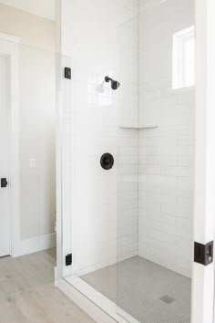 a white tiled shower with black handles and knobs on the door is shown in this bathroom