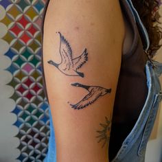 a woman with a tattoo on her arm that has two birds flying in the sky