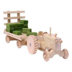 a wooden toy truck with green blocks in the back and wheels on it's side