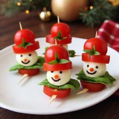 small tomatoes with tomato faces on them sitting on a white plate next to a christmas tree