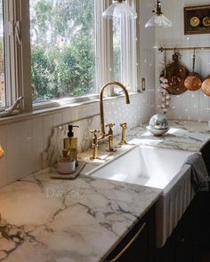 a kitchen with marble counter tops and gold faucets on the windowsills