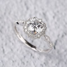 a white gold ring with a diamond center surrounded by pave diamonds on a snow covered surface