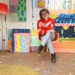 a woman sitting on top of a chair in front of paintings