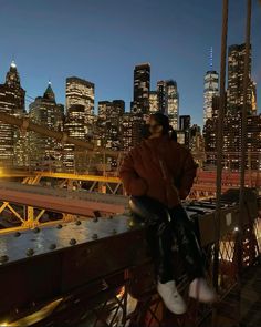 a woman sitting on top of a bridge next to a city