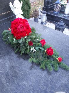 red roses and greenery are placed on the headstone