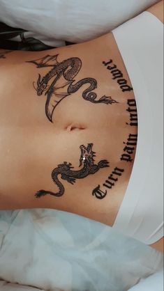 a woman's stomach with tattoos on it and the words dragon written in cursive writing